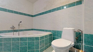 Koupelna s dlažbou v zelenobílém provedení, zahrnující rohovou vanu a moderní toaletu, působí svěže a prakticky.