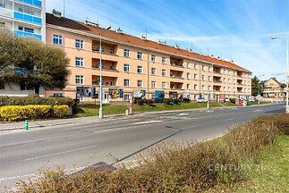 Prostorný bytový dům s balkony, cihlová fasáda, blízkost hlavní silnice, pohodlná dostupnost k veřejné dopravě, klidná rezidenční lokalita.