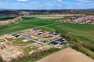 Nově vznikající rezidenční čtvrť s rodinnými domy, moderní stavby, klidné okolí, blízkost přírody, příjezdové cesty, rozlehlé zelené plochy.