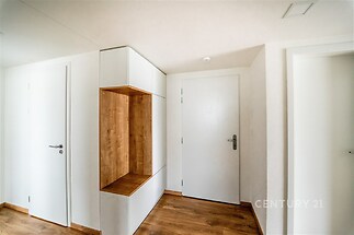Chodba s parketovou podlahou, vestavěnými skříněmi a moderním designem, nabízí praktické úložné prostory a elegantní dřevěné detaily.