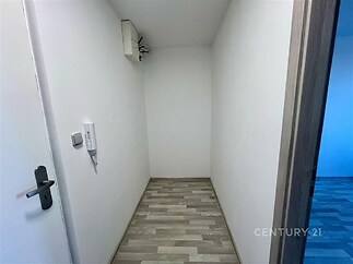 Úzká chodba s parketovou podlahou, bílými stěnami a dveřmi, nabízí moderní design a jednoduché uspořádání.