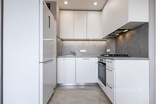 Moderní kuchyň, světlá dlažba a vestavěné spotřebiče, minimalistický design a funkčnost zajišťují komfortní prostředí pro vaření.