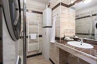 Moderní koupelna s dlažbou, vestavěnými spotřebiči a praktickým topným žebříkem nabízí světlý, dobře udržovaný prostor.