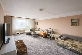 Prostorný obývací pokoj se světlým koberce, velkými okny a útulným nábytkem, nabízí světlý interiér s moderním designem.