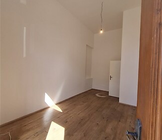 Světlý pokoj s parketovou podlahou a vysokými stropy, moderní vzhled, ideální pro rekonstrukci nebo úpravy podle vlastních představ.