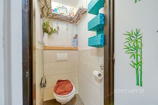 Malá koupelna s moderní dlažbou, závěsným WC a praktickým úložným prostorem. Elegantní dekorativní prvky a decentní osvětlení poskytují útulný pocit.