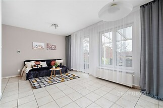 Světlý obývací pokoj s dlažbou, velkými okny a moderním vybavením, ideální pro rodinný život.