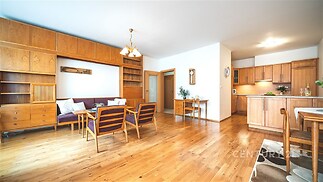 Světlý obývací pokoj s parketovou podlahou, vestavěným dřevěným nábytkem a moderním designem nabízí pohodlné a stylové bydlení.