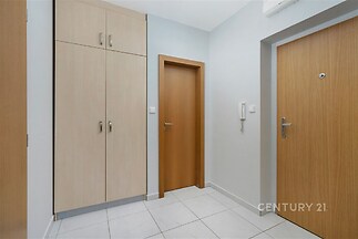 Vstupní hala s moderními vestavěnými skříněmi, světlá dlažba a dřevěné dveře vytvářejí stylový a praktický prostor.