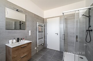 Moderní koupelna s dlažbou, sprchovým koutem a dřevěnou skříňkou. Světlé a rekonstruované prostory s topným žebříkem poskytují komfort.