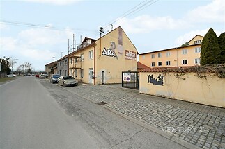 Exteriér komerční budovy s fasádou v ulici, parkoviště, zděné oplocení, klidná lokalita, ideální pro podnikání.