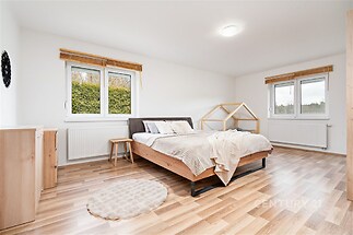 Prostorná ložnice s parketovou podlahou, velkými okny a moderním nábytkem, poskytuje světlý a vzdušný prostor pro pohodlné bydlení.