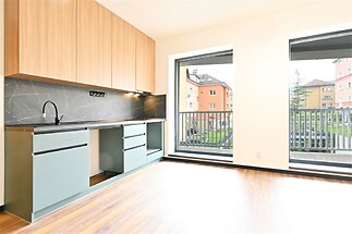 Moderní kuchyň s parketovou podlahou, vestavěnými skříněmi a velkými okny prosvětlujícími prostor.