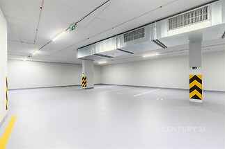 Parkovací garáž s hladkou betonovou podlahou, moderní osvětlení, ventilační systém, vhodné pro více vozidel, výborný stav.