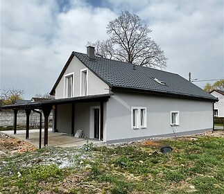 Moderní rodinný dům s tmavou střechou, novou fasádou a prostornou terasou, situovaný v klidné lokalitě s velkým pozemkem.