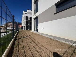 Novostavba s moderní fasádou a francouzskými okny, zahrada se zpevněnou plochou, situovaná v klidné části města.