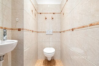 Koupelna s keramickými obklady, světlé dlažby, závěsné WC, umyvadlo a moderní design.