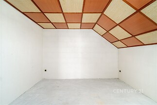 Podkrovní pokoj s dřevěným obložením stropu, betonovou podlahou a bílými stěnami, ideální pro rekonstrukci nebo kreativní využití prostoru