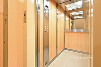 Moderní výtah s nerezovým ovládacím panelem a zrcadlem, vybavený světlým dřevěným obložením stěn, poskytuje pohodlný přístup v budově.