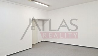 Prázdný pokoj s bílými stěnami, moderní stropní osvětlení, šedá kobercová podlaha, vhodný pro rekonstrukci nebo jako obchodní prostor