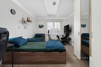Ložnice s parketovou podlahou, vestavěnými skříněmi a velkými okny nabízí moderní a světlý interiér v komfortním stylu.