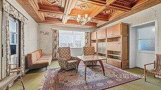 Obývací pokoj s dřevěným stropem, světlým kobercem a velkými okny, retro styl s nábytkem z 60. let, ideální pro renovaci.