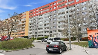 Vícepodlažní bytový dům s balkony, moderní fasáda, městské prostředí.