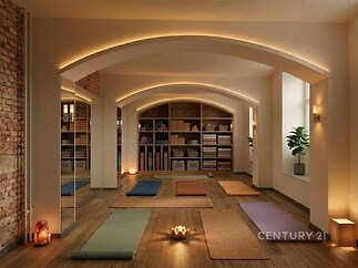 Jógové studio s dřevěnou podlahou, velkými okny a moderním osvětlením nabízí útulný prostor pro relaxaci a cvičení.