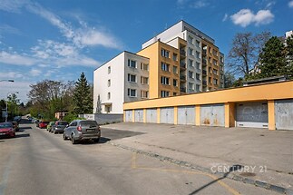 Vícepodlažní bytový dům s moderní fasádou, parkování před garážemi, klidná rezidenční lokalita, blízko zeleně a s dobrou dopravní dostupností.