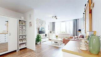 Světlý obývací pokoj s parketovou podlahou, velkými okny a moderním nábytkem, vytváří svěží atmosféru.