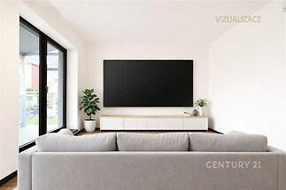 Světlý obývací pokoj s moderní sedačkou, velkými okny a parketovou podlahou, vytvářející prostor plný přirozeného světla.