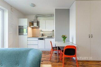 Moderní kuchyň s parketovou podlahou, světlá díky velkým oknům, vybavená vestavěnými spotřebiči a moderním nábytkem