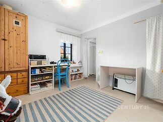 Dětský pokoj s dlažbou, dřevěnou skříní a velkým oknem, světlý a prostorný, ideální pro kreativní aktivity a studium.