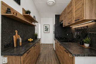 Moderní kuchyň s dřevěnou linkou, kamennou pracovní deskou, vestavěnými spotřebiči a parketovou podlahou, ideální pro rodinné vaření.