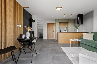 Moderní obývací pokoj s dlažbou, otevřenou kuchyní a stylovým dřevem na stěnách. Světlý a prostorný interiér s moderním nábytkem.