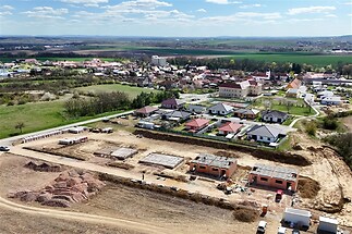 Stavební pozemek s rozestavěnými domy, moderní rezidenční čtvrť, přírodní okolí, perspektivní lokalita blízko města.