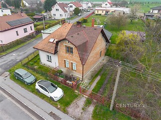 Rodinný dům s cihlovou fasádou, prostornou zahradou a šikmou střechou v klidné rezidenční oblasti.