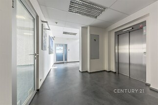 Světlá vstupní hala s dlažbou, moderní výtah a prosklené dveře, zajišťující přirozené světlo, zachovávají svěží a funkční design budovy.