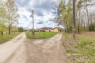 Příjezdová cesta vede k venkovskému domu obklopenému zelení, který je částečně rekonstruovaný a nabízí klidnou lokalitu.