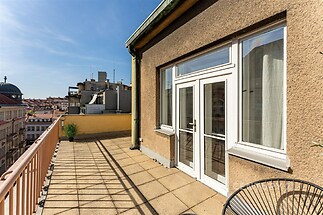 Velká terasa s dlažbou a velkými okny, nabízí krásný výhled na městskou panoramu, ideální pro moderní bydlení v centru města.
