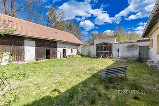 Uzavřený dvůr s travnatou plochou, obklopený stodolou a kamennou zdí, ideální pro rekonstrukci nebo venkovské bydlení, slunné prostředí.