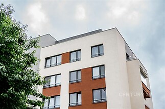 Moderní bytová budova s velkými okny a rekonstruovanou fasádou kombinuje bílou a cihlově červenou barvu pro stylový vzhled.