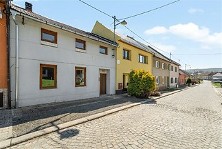 Fasáda rodinného domu s novými okny, klidná dlažba před domem, zaměřená na modernizovanou řadovou zástavbu v Tiché ulici.