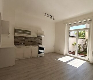 Moderní kuchyň s parketovou podlahou, velké francouzské okno a světlý interiér, ideální pro otevřený obytný prostor