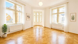 Světlý obývací pokoj s parketovou podlahou, velkými okny a moderním stylem.