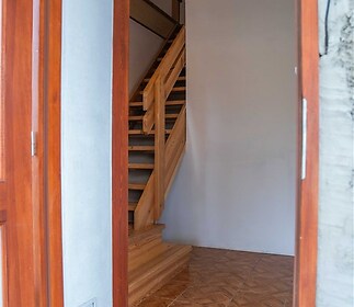 Vstupní hala s dřevěným schodištěm, dlažbou a dřevěnými rámy oken, minimalistický styl, rekonstrukce.
