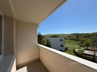Balkon s výhledem na zeleň a okolní budovy, světlý prostor s dlažbou, ideální pro relaxaci, klidná lokalita