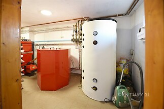 Technická místnost s moderním vytápěním a dlažbou, obsahující kotel a zásobník na vodu, ideální pro energeticky úsporný dům.