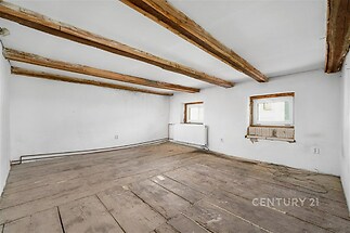 Prostorná místnost s dřevěnými trámy, staré dřevěné podlahy, přírodní prvky. Potenciál pro rekonstrukci a modernizaci, světlý interiér.