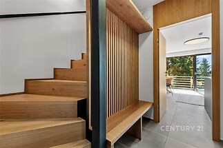 Dřevěné schodiště spojující moderní interiér s otevřeným prostorem, dlažba v chodbě, světlý design s přírodními prvky
